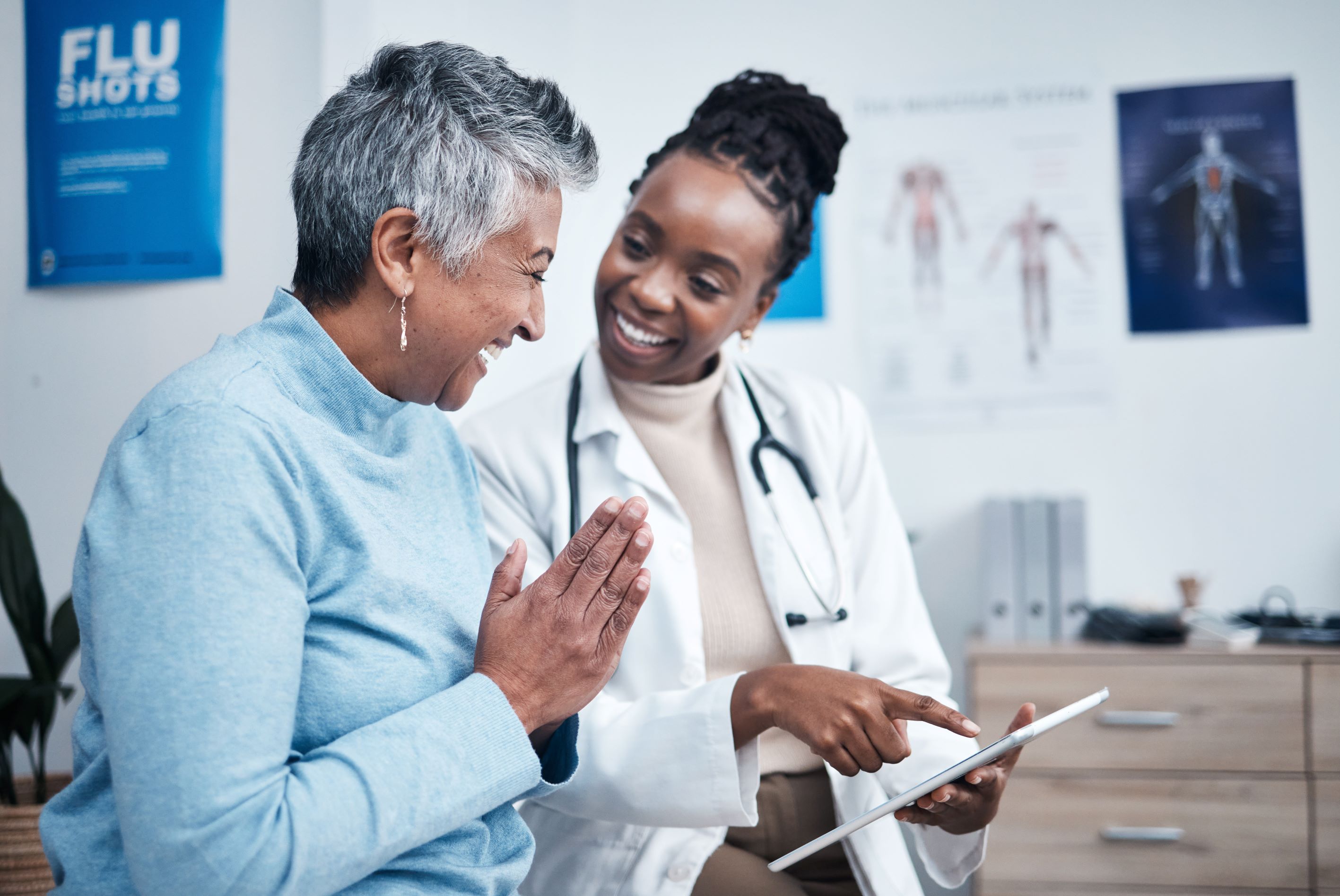 Senior woman smiles as she consults with doctor using a tablet at appointment.